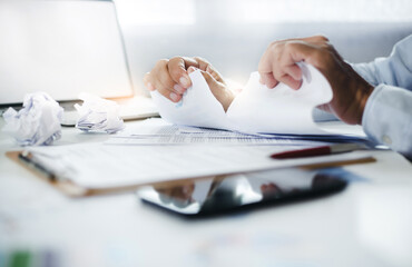 Asian businessman tearing up document or contract while sitting at the table he suffered a loss in...