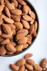 Bowl of fresh almonds in bowl on white marble background. Top view. Close-up.
