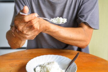 Elderly man is holding his hand while eating because Parkinson's disease.Tremor is most symptom and...