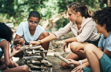 Building friendships and learning new skills. a group of teenagers building a pile of wood at summer camp.