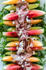 Slices of watermelon, cantaloupe and cucumber topped with prosciutto and feta.