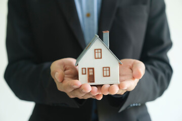 Close up real estate agent holding house model for consult the client.