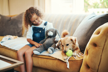 Enjoying home time with my dog. an adorable young girl sitting on the sofa at home and bonding with...
