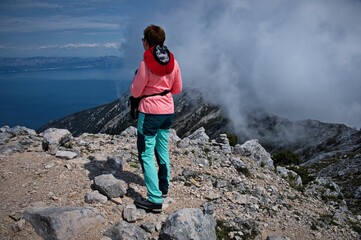 Fototapeta premium Rear view of senior woman hiking in rocky landscape in Croatia