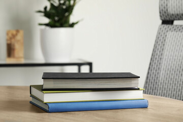 Many different books stacked on wooden table indoors