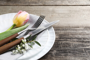 Stylish table setting with cutlery and flowers on wooden background. Space for text