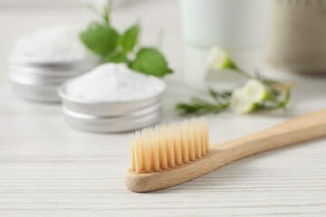 Toothbrush, dental products and herbs on white wooden table, closeup