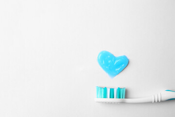 Heart made with toothpaste and brush on white background, top view. Space for text