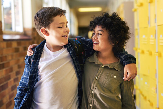 Were Best Friends. Two Young Boys Standing In The Hallway At School With Their Arms Around Each Other.