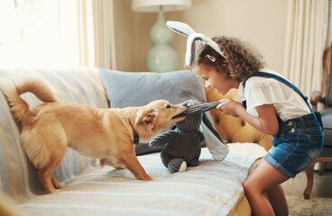Nothing beats a good old game of tug and war. an adorable young girl standing in the living room at home and playing with her dog. - obrazy, fototapety, plakaty