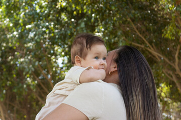 Madre cargando a su bebé, día soleado, rodeados de naturaleza