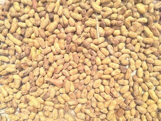 A pile of peanuts on a concrete surface.
