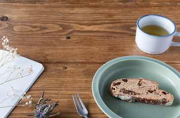 Break for baked goods and tea on a brown wooden table decorated with notebooks and dried flowers