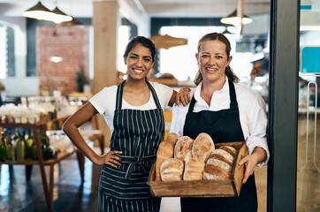 Nobody bakes it better than we do. two women holding a selection of freshly baked breads in their...