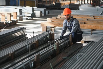 Portrait of Professional Heavy Industry Engineer Worker Wearing Safety Uniform, Hard Hat Smiling. In the Background Unfocused Large Industrial Factory.