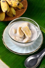 Banana in coconut milk,Traditional Thai desserts in a bowl on a banana leaf with Black background. Cultivated banana dessert.Vegetarian food.