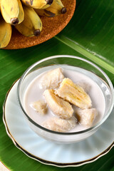 Banana in coconut milk,Traditional Thai desserts in a bowl on a banana leaf with Black background. Cultivated banana dessert.Vegetarian food.