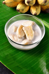 Banana in coconut milk,Traditional Thai desserts in a bowl on a banana leaf with Black background. Cultivated banana dessert.Vegetarian food.