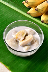 Banana in coconut milk,Traditional Thai desserts in a bowl on a banana leaf with Black background. Cultivated banana dessert.Vegetarian food.