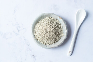 French green clay in white ceramic plate, cosmetic clay powder.