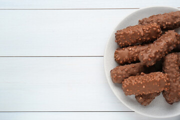 Tasty sweet chocolate bars on white wooden table, top view. Space for text