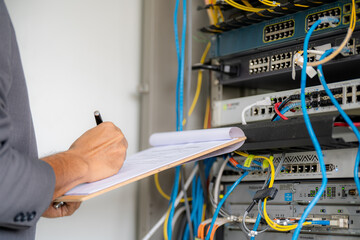 IT administrator technicians take notes and monitor network systems in the server room.