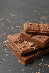 Pieces of tasty chocolate on grey table, closeup
