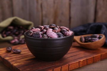 Bowl with dry kidney beans on wooden table, closeup