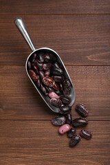 Metal scoop with dry kidney beans on wooden table, flat lay