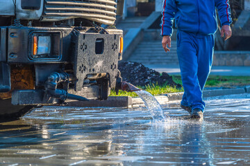 Water pours from the irrigation machine onto the asphalt.