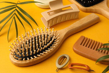 Wooden brushes, comb and different hair products on orange background