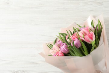 Bouquet of beautiful tulips on white wooden table, top view. Space for text