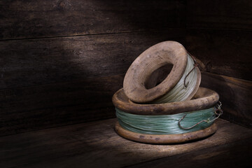 Two old wooden hand fishing reels lines rusty hooks rustic wooden setting spotlight mood lighting copy space  