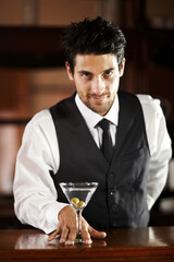 Man, portrait and giving cocktail at bar for service, drink and welcome to party, club or event. Male server, barman or waiter with glass for alcohol, spirit or mixer with presentation at restaurant