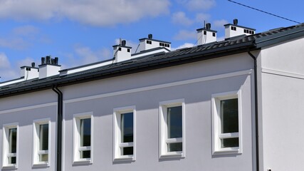 Terraced family homes in newly developed housing estate. The real estate market in the suburbs. New single family houses in a new development area. Residential homes with modern facade. 