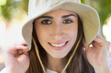 Face, smile and close up of woman with hat or lady with natural beauty on a sunny day or hiker on bokeh background. Head cap, portrait and happy female tourist or summer leisure and recreation