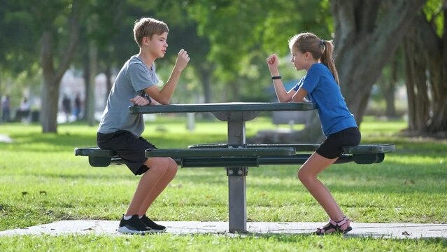 Happy kids boy and girl playing rock paper scissors in summer park on sunny day. Concept of competition between children