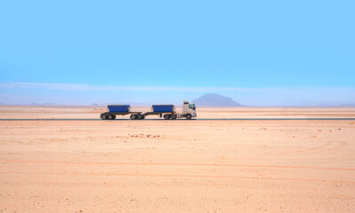 Semi-trailer truck speeds along the motorway running across the desert - Namibia