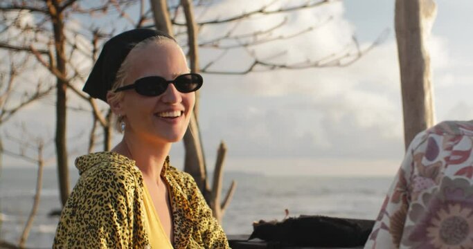 Illuminated by golden sunlight young woman sincerely laughs at camera