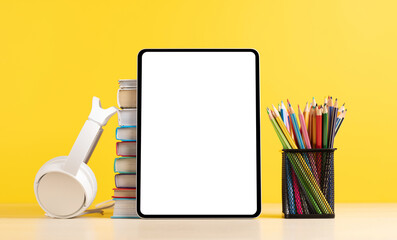 Tablet with colorful pencils and stack of books