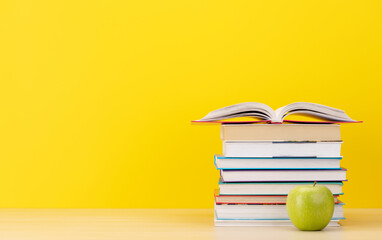 Stack of books on desk and apple