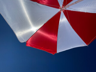 Red and White beach umbrella against blue sky