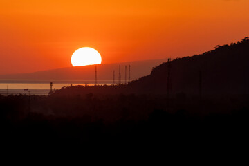 Obraz premium Sun rising behind mountain above the ocean in Indonesia