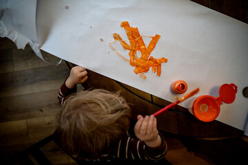 Blonde Toddler Boy Painting on White Paper with Orange Paint
