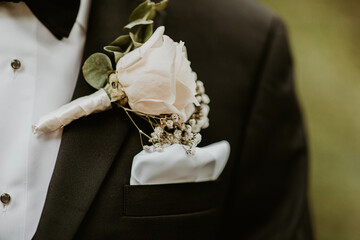 Pinned white rose wedding boutonnière with baby's breath