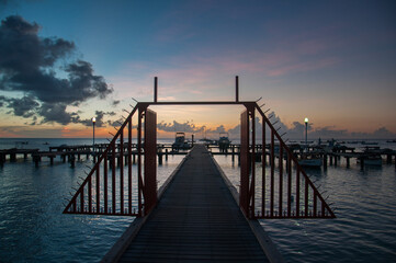 Fototapeta na wymiar Dock with boats and sailboats on a beach in Aruba, at sunset, Ne