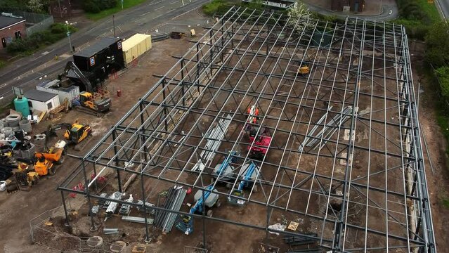 Aerial lifting view over Aldi grocery store building site foundation steel framework and construction equipment
