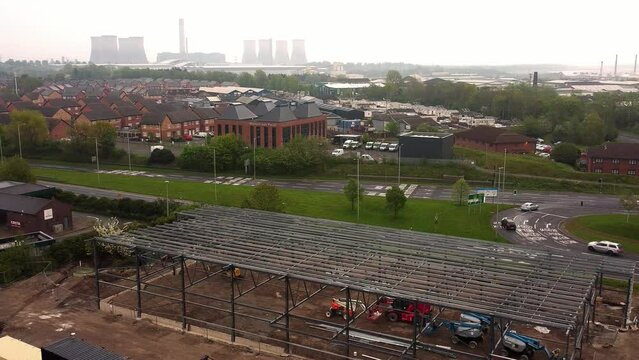 Aerial descending view of Aldi grocery store building site foundation steel framework under power station horizon