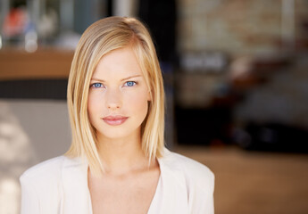 Face, young serious woman at her office and in a blurred background. Portrait of confident or proud person, corporate manager or worker and closeup of female professional with focus in Denmark