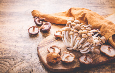 Raw brown shimeji mushrooms and shiitake on cutting board